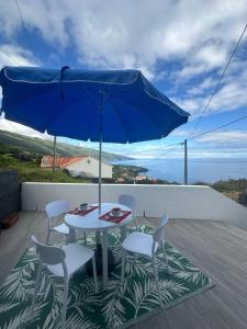 a table and chairs with a blue umbrella on a balcony at Quinta da Baía - AL in Arrife