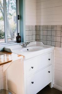 a white sink in a bathroom with a window at Little Vineyard Caboose in Drummond