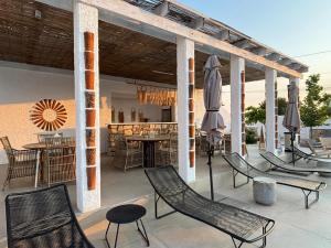 a patio with chairs and tables and an umbrella at Vila Alaris Vama Veche in Vama Veche