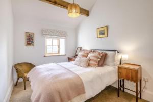 una camera da letto con un letto, una sedia e una finestra di Lapwing Cottage a Cowling