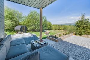 een terras met een blauwe bank en een hottub bij Deer Cottage in Eldroth