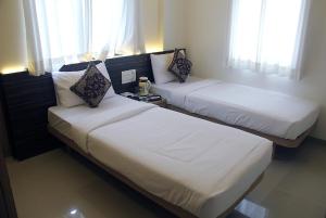 two beds in a hotel room with windows at Hotel SaiPrasad Executive Solapur in Solapur