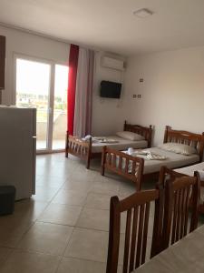 a room with three beds and a tv and a window at Hotel Armela in Velipojë