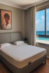 a bedroom with a bed and a large window at מגדל אלמוג חיפה - דירות "בלו ביץ'" על הים in Haifa +59 photos