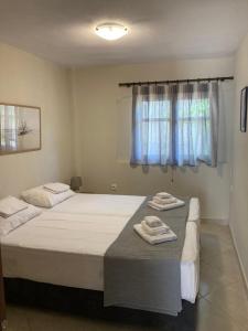 a bedroom with two beds and a window with towels at Aldebaran house in Nea Fokea