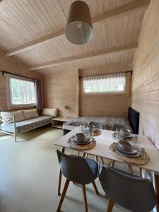a room with a table and chairs and a couch at Sosenkowo Domki Letniskowe in Pobierowo