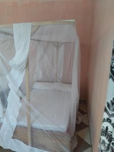 a small bed in a room with white curtains at Momi Home Stay in Utende