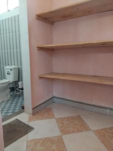 a bathroom with wooden shelves and a toilet at Momi Home Stay in Utende