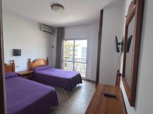 a hotel room with two beds and a balcony at Hostal Susi in Peñíscola