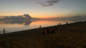 a group of people sitting on the beach at sunset at FLAMBOYANT - Studio 2 personnes avec lit de qualité hôtelière séparable pour couple ou amis avec très belle terrasse à 12 min à pied ou 4 min en voiture du lagon de l'Ermitage - ST GILLES LES BAINS in La Saline les Bains +1 photo