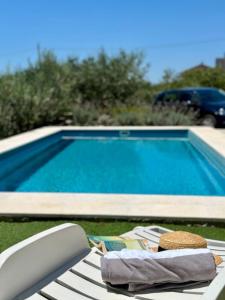 a table with a towel and a book next to a swimming pool at Eden Holiday House with private Pool and Vineyard in Kaštela
