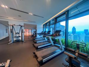 a gym with a row of tread machines and a window at Eaton Residences KLCC - Luxury Apartment in Kuala Lumpur