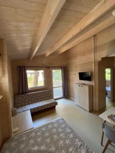 a room with a couch and a tv in a room at Sosenkowo Domki Letniskowe in Pobierowo