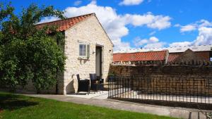 a stone house with a fence and a table and chairs at The Bothy in Carlton