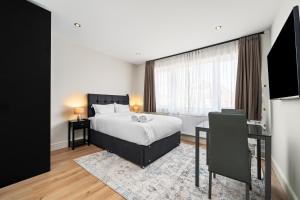 Un dormitorio con una cama y un escritorio y una ventana. en Willesden Green City Suites, en Londres