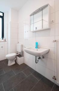 a white bathroom with a sink and a toilet at Rock City Apartments Room 5150 in Essen