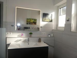 a white bathroom with a sink and a mirror at Ferienhaus Schmidt in Beerfelden +23 photos