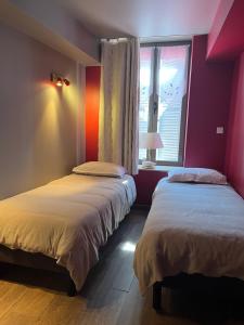 two beds in a room with a window at Aux Cornettes in Beaune