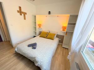 a small room with a bed and a cross on the wall at Le Cocon Ruthenois in Rodez