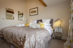a bedroom with a large bed with white and yellow pillows at Hare Cottage in Finghall