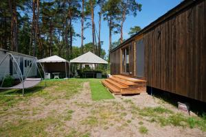 un cortile con una panca di legno e una tenda di Nowy leśny domek a Dziwnów