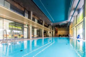 a large swimming pool with blue water in a building at Omega Lake Apartments in Olsztyn