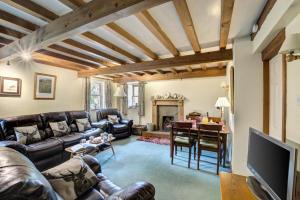 ein Wohnzimmer mit Ledermöbeln und Kamin in der Unterkunft West Cottage in Thwaite