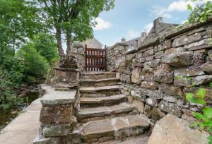 eine alte Steinmauer mit Treppe und einer Bank in der Unterkunft West Cottage in Thwaite