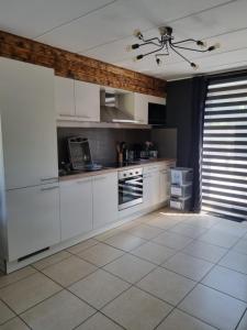a kitchen with white cabinets and a tile floor at La parenthèse in Marche-en-Famenne
