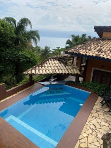 une grande piscine bleue à côté d'une maison dans l'établissement Vila Costa Sul Chalés e Estúdios, à Ilhabela