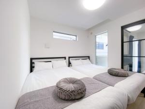a white bedroom with two beds with pillows on them at GLITTER302 Max 6ppl 5 minutes to USJ by train in Osaka