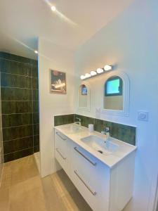 a white bathroom with a sink and a shower at La Chaumière en bord de mer in Trégastel