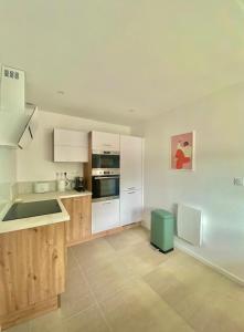 a kitchen with white appliances and wooden cabinets at La Chaumière en bord de mer in Trégastel