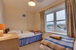 two beds in a room with a window at Blacksmiths Cottage in Catterick Bridge
