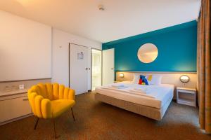a hotel room with a bed and a yellow chair at Hessenland Hotel Kassel Innenstadt by Stay Awesome in Kassel