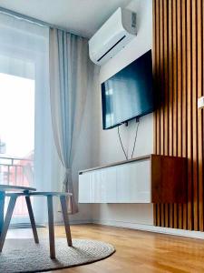 ein Wohnzimmer mit einem Tisch und einem Flachbildfernseher in der Unterkunft Apartman Lena in Vrnjačka Banja