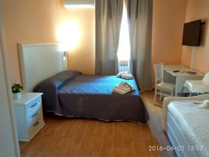 um pequeno quarto com uma cama, uma secretária e uma janela em Le Camelie em Ginosa Marina
