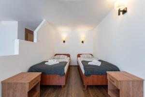 two twin beds in a room with two tables at DIUNA Łeba in Łeba +38 photos