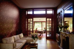 a living room with a couch and a person sitting at a table at B&B De Gilleminus in Temse