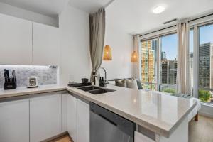 a kitchen with white cabinets and a large window at Cityview Suite near Robson Square and Canada Place for 6 Guests in Vancouver