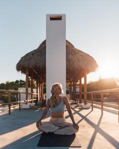 a woman is sitting in a yoga pose on the floor at Casa Ohma La Punta in Brisas de Zicatela