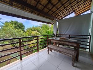 un banc sur un balcon avec vue sur la forêt dans l'établissement Reserva Imbassaí Apartamento 1 quarto área de churrasco Bl2202, à Mata de São João