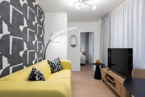 a living room with a yellow couch and a tv at Smartr Valencia Turia in Valencia