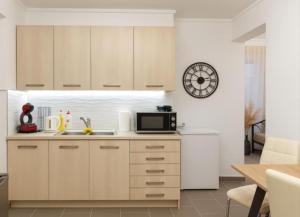 a kitchen with white cabinets and a microwave at VE Apartment in Khelmáta