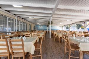 a dining room with tables and chairs and windows at DIUNA Łeba in Łeba
