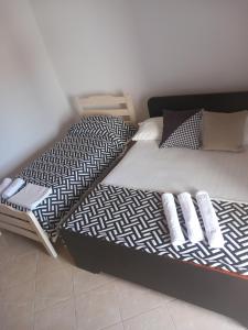 a twin bed with black and white sheets and pillows at Dario's Apartaments in Orikum