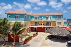 a blue and yellow house with palm trees and the ocean at Ocean View Apartment Flounder at Den Laman in Kralendijk