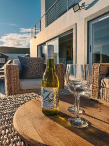 a bottle of wine and a wine glass on a table at Agapé Villa Agulhas in Agulhas