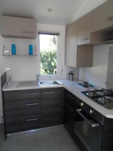 a kitchen with a sink and a stove top oven at Mobil home 6 personnes Mer et Pins in Piriac-sur-Mer +5 photos