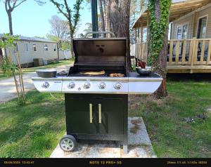 a barbecue grill sitting in a yard next to a house at Mobil home 6 personnes Mer et Pins in Piriac-sur-Mer